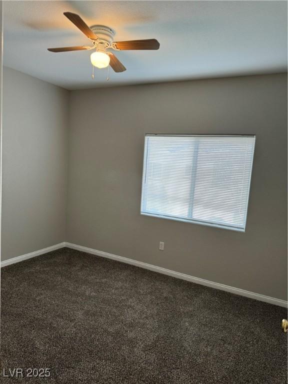 unfurnished room featuring a ceiling fan, dark carpet, and baseboards