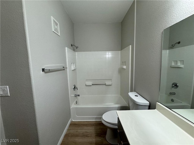 full bathroom with visible vents, toilet, wood finished floors, vanity, and bathtub / shower combination