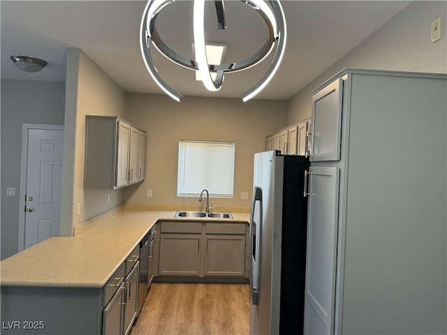 kitchen featuring appliances with stainless steel finishes, gray cabinetry, light wood-type flooring, and a sink