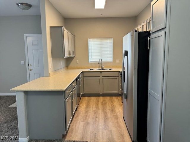 kitchen featuring light wood-style floors, stainless steel fridge with ice dispenser, gray cabinets, and a sink