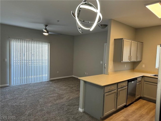 kitchen with ceiling fan, a peninsula, light countertops, stainless steel dishwasher, and gray cabinetry