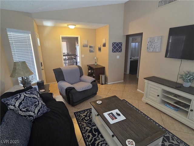 7328 Coffeyville Ave, Las Vegas, NV 89147 - living room featuring light tile patterned floors, visible vents, vaulted ceiling, and baseboards
