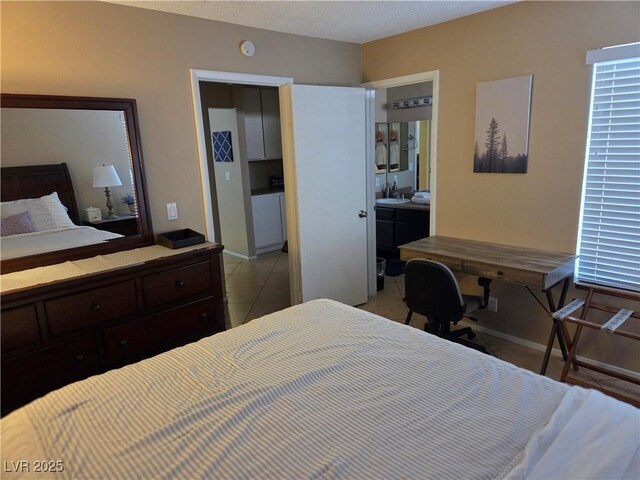 7328 Coffeyville Ave, Las Vegas, NV 89147 - bedroom featuring light tile patterned floors, a sink, connected bathroom, and baseboards