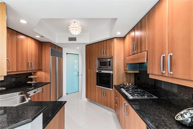 2857 Paradise Rd Unit 305, Las Vegas, NV 89109 - kitchen featuring built in appliances, a raised ceiling, brown cabinetry, ventilation hood, and a sink