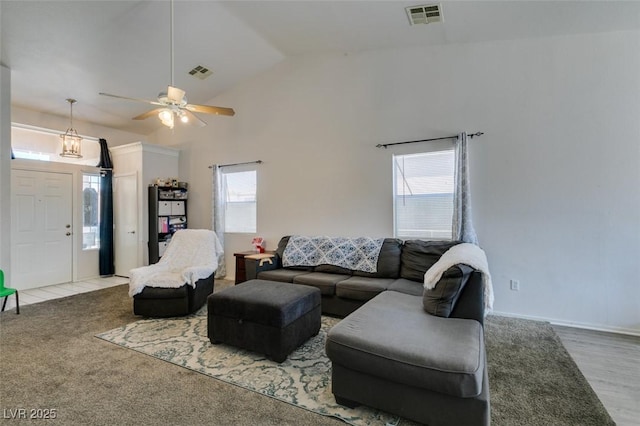 living area with a ceiling fan, visible vents, and lofted ceiling