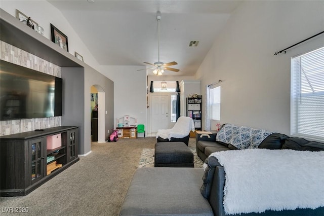 living area with a wealth of natural light, visible vents, vaulted ceiling, arched walkways, and carpet floors