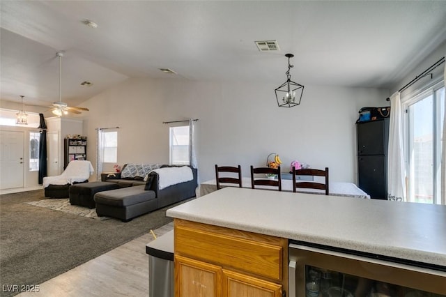 kitchen featuring beverage cooler, light wood-style floors, vaulted ceiling, visible vents, and pendant lighting