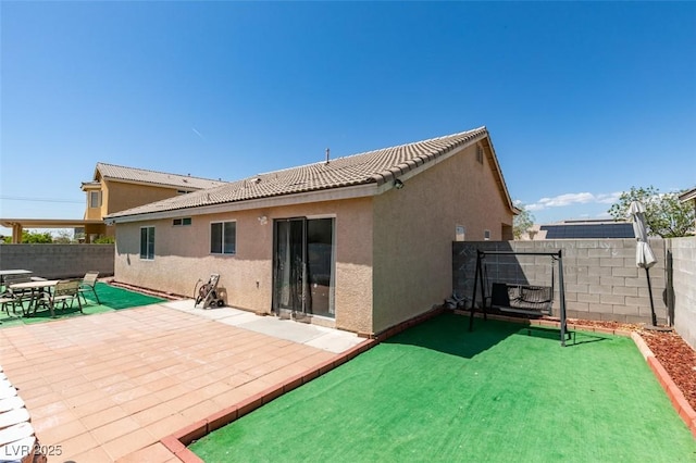 rear view of house featuring a patio, stucco siding, a fenced backyard, and a tiled roof