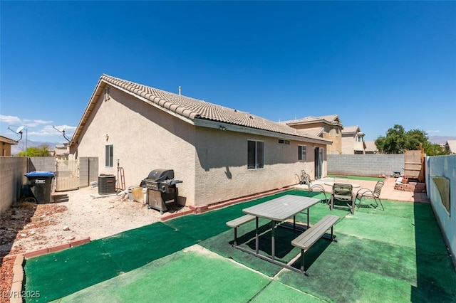 rear view of property featuring a fenced backyard, stucco siding, a tiled roof, and a patio area
