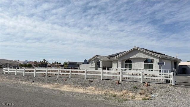 view of front of property featuring stucco siding, solar panels, and a fenced front yard