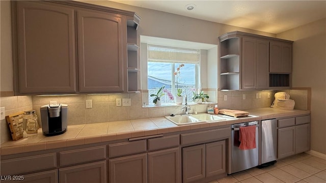 kitchen with stainless steel dishwasher, open shelves, backsplash, a sink, and light tile patterned flooring