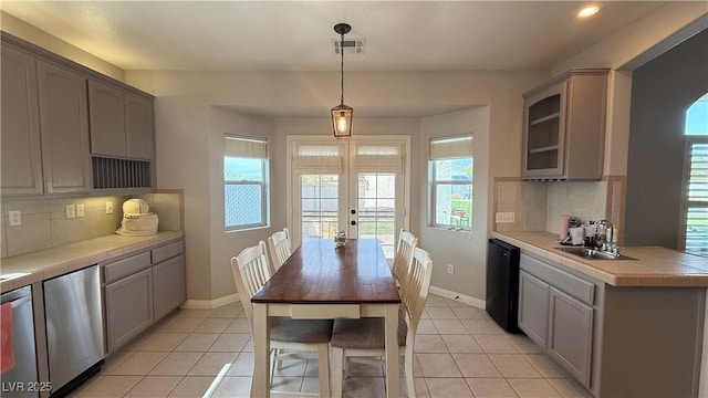 kitchen featuring a wealth of natural light, black dishwasher, tile counters, a sink, and visible vents