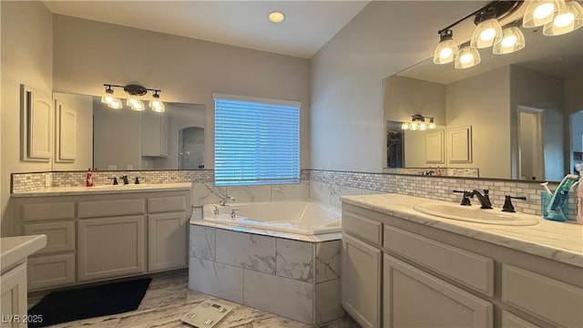 bathroom featuring a bath, two vanities, a sink, and backsplash