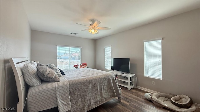 bedroom with dark wood finished floors, visible vents, a ceiling fan, and baseboards