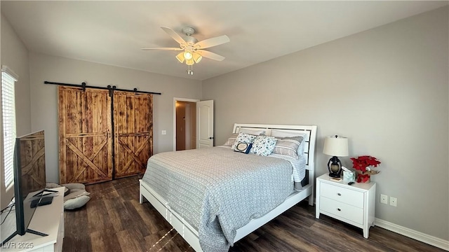 bedroom featuring dark wood-style floors, a ceiling fan, a barn door, and baseboards