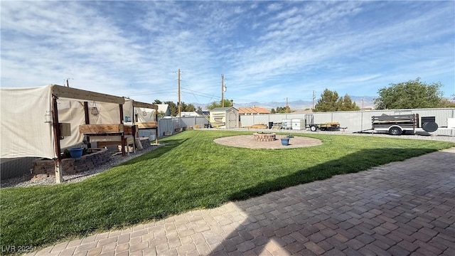 view of yard with a fire pit, an outdoor structure, a patio, a storage unit, and fence