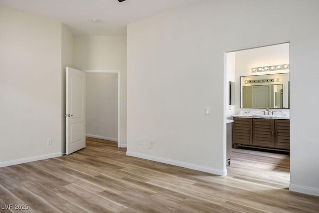 10657 Sapphire Vista Ave, Las Vegas, NV 89144 - unfurnished bedroom featuring a sink, baseboards, connected bathroom, and light wood-style floors