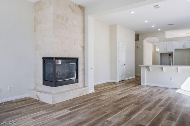 10657 Sapphire Vista Ave, Las Vegas, NV 89144 - unfurnished living room featuring a tiled fireplace, recessed lighting, light wood-style flooring, and baseboards