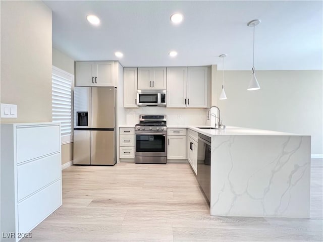 8070 W Russell Rd Unit 2070, Las Vegas, NV 89113 - kitchen featuring a sink, a peninsula, light stone counters, hanging light fixtures, and appliances with stainless steel finishes