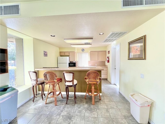 8070 W Russell Rd Unit 2070, Las Vegas, NV 89113 - kitchen with a breakfast bar, black microwave, visible vents, and freestanding refrigerator
