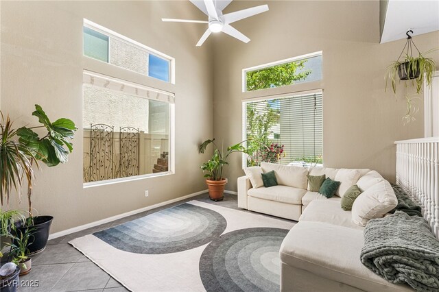 tiled living room featuring baseboards, high vaulted ceiling, and ceiling fan