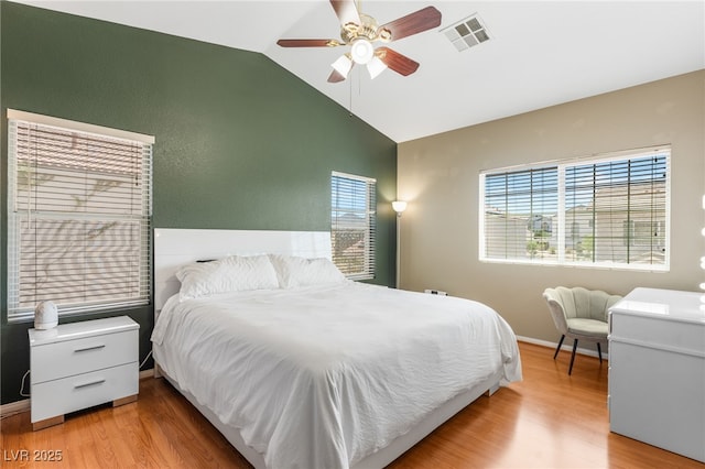 bedroom with visible vents, baseboards, wood finished floors, a ceiling fan, and high vaulted ceiling
