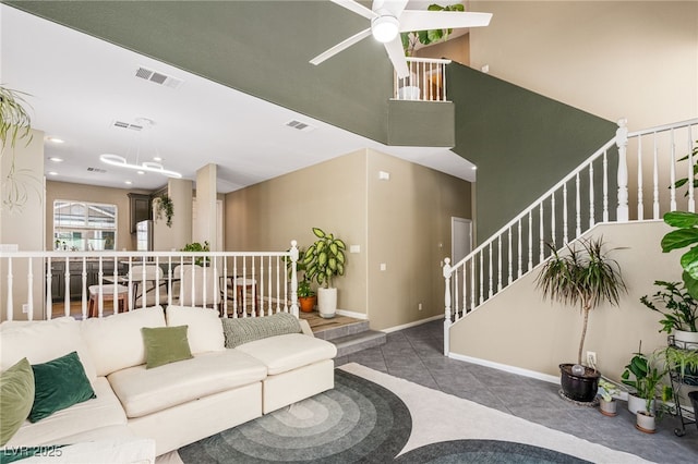 living room with tile patterned floors, visible vents, ceiling fan, and stairs