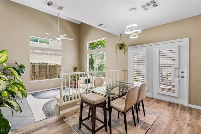 dining space featuring visible vents, ceiling fan with notable chandelier, and light wood-style flooring