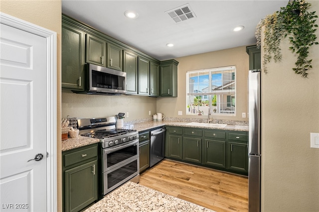 kitchen with appliances with stainless steel finishes, green cabinetry, visible vents, and a sink