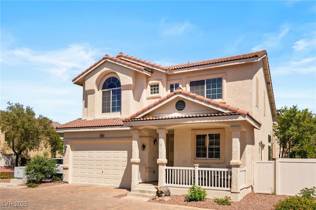 mediterranean / spanish home featuring driveway, covered porch, a tiled roof, and stucco siding