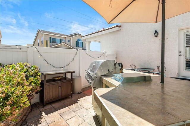 view of patio / terrace featuring fence, area for grilling, and exterior kitchen