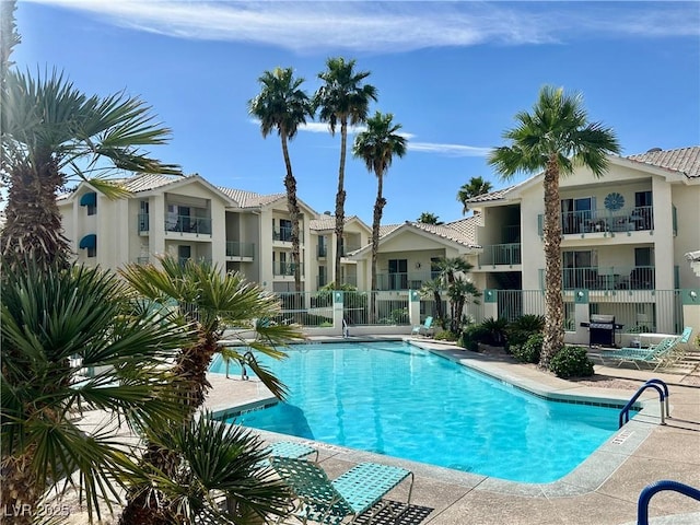 community pool with fence, area for grilling, and a residential view