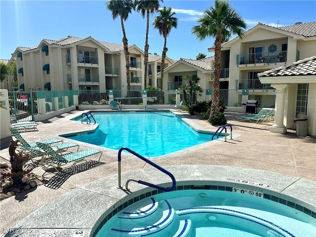 pool featuring a community hot tub, a patio area, and fence