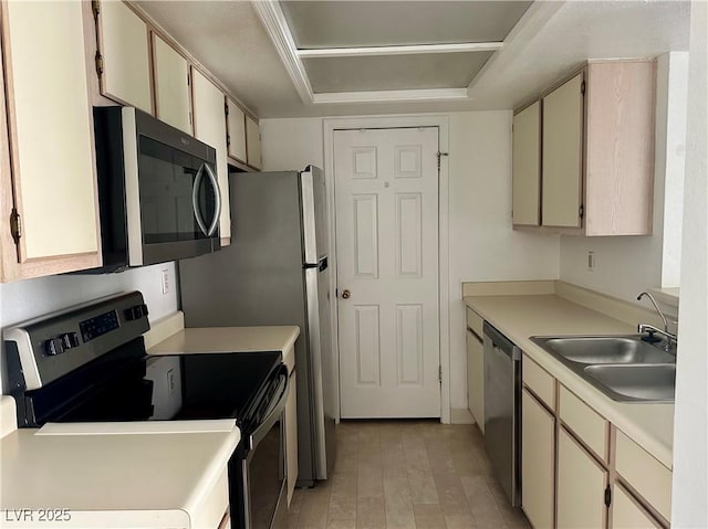 kitchen with a sink, stainless steel appliances, light countertops, light wood finished floors, and cream cabinets