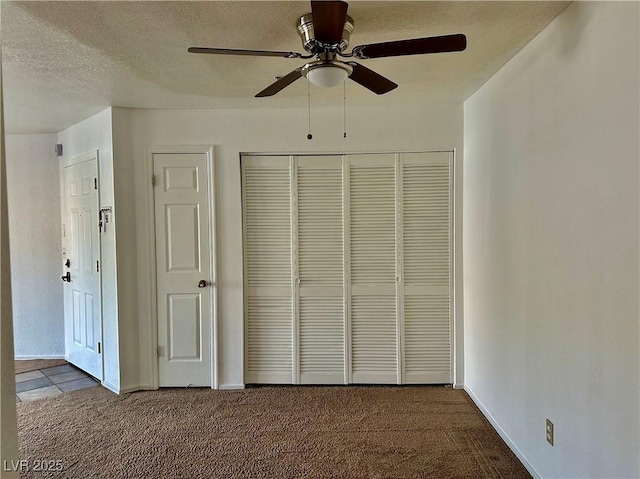 unfurnished bedroom featuring carpet floors, a closet, ceiling fan, baseboards, and a textured ceiling