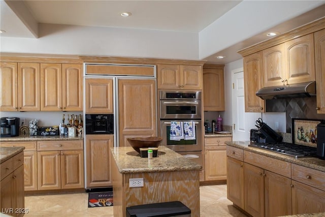 9905 Fox Springs Dr, Las Vegas, NV 89117 - kitchen with appliances with stainless steel finishes, under cabinet range hood, light stone countertops, light brown cabinetry, and recessed lighting