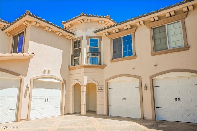 view of front of house featuring stucco siding, an attached garage, and a tile roof