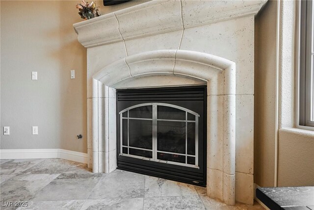 interior details featuring a glass covered fireplace and baseboards
