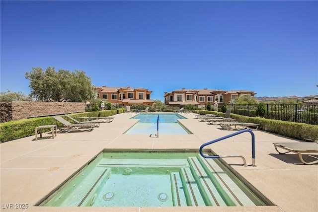 pool with fence, a patio area, and a hot tub