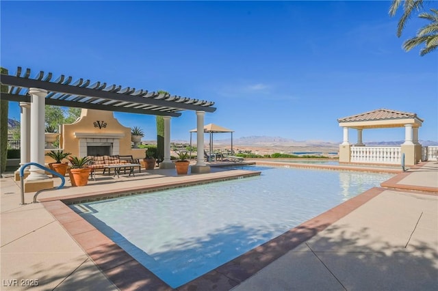 view of swimming pool featuring a patio, a pergola, exterior fireplace, a mountain view, and a gazebo