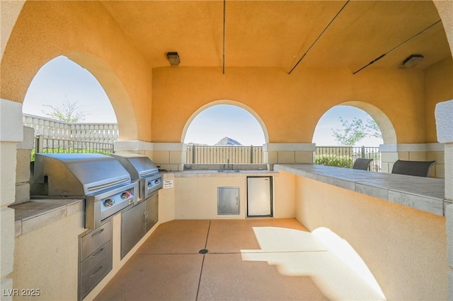 view of patio with fence, grilling area, and an outdoor kitchen