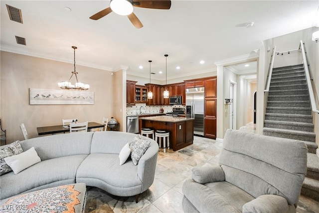 living area featuring visible vents, ornamental molding, ceiling fan with notable chandelier, and stairway