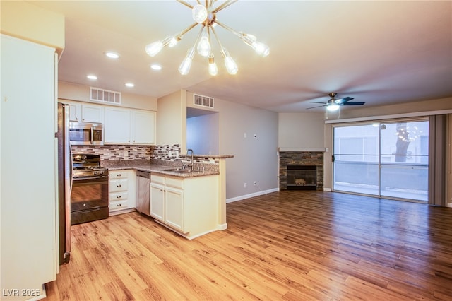kitchen with a sink, appliances with stainless steel finishes, visible vents, open floor plan, and a peninsula