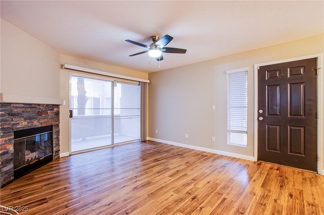 unfurnished living room with baseboards, a ceiling fan, light wood-style floors, and a fireplace