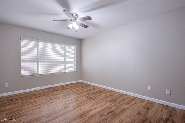 spare room with baseboards, wood finished floors, and ceiling fan