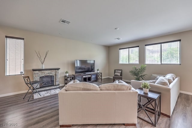 living area featuring a fireplace, visible vents, wood finished floors, and baseboards