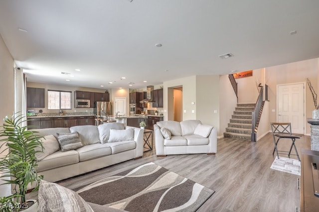 living room with stairway, light wood-type flooring, recessed lighting, and baseboards