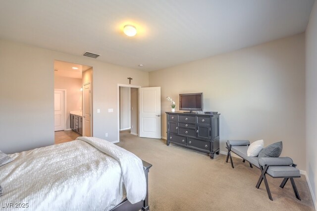 bedroom with visible vents, ensuite bath, light colored carpet, and baseboards