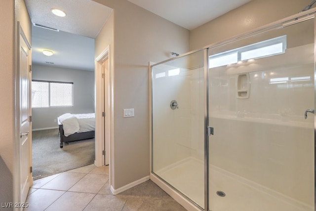 bathroom featuring tile patterned floors, visible vents, a shower stall, and baseboards