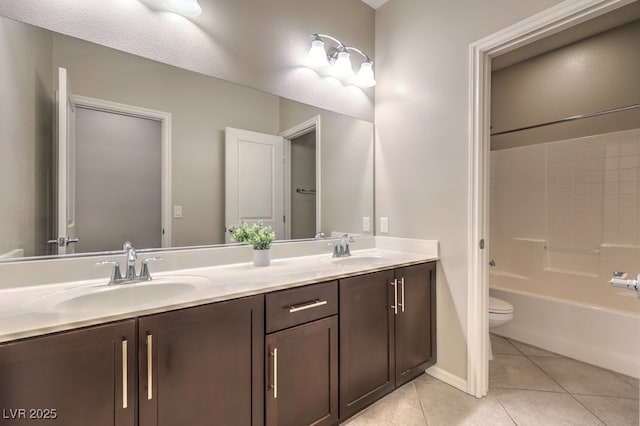 full bathroom with toilet, double vanity, a sink, and tile patterned floors